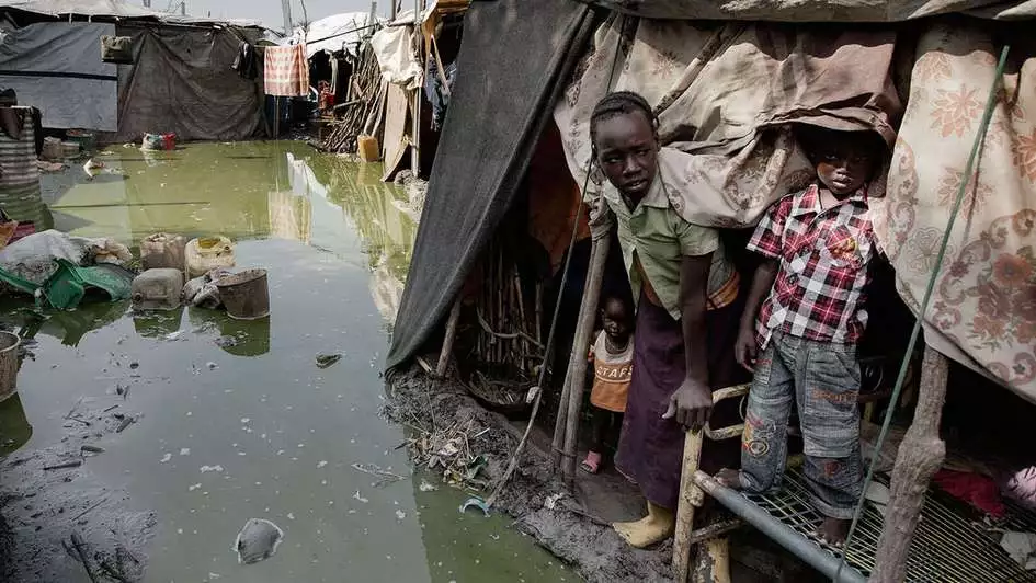 Family looks out of their tent. Everything is flooded.