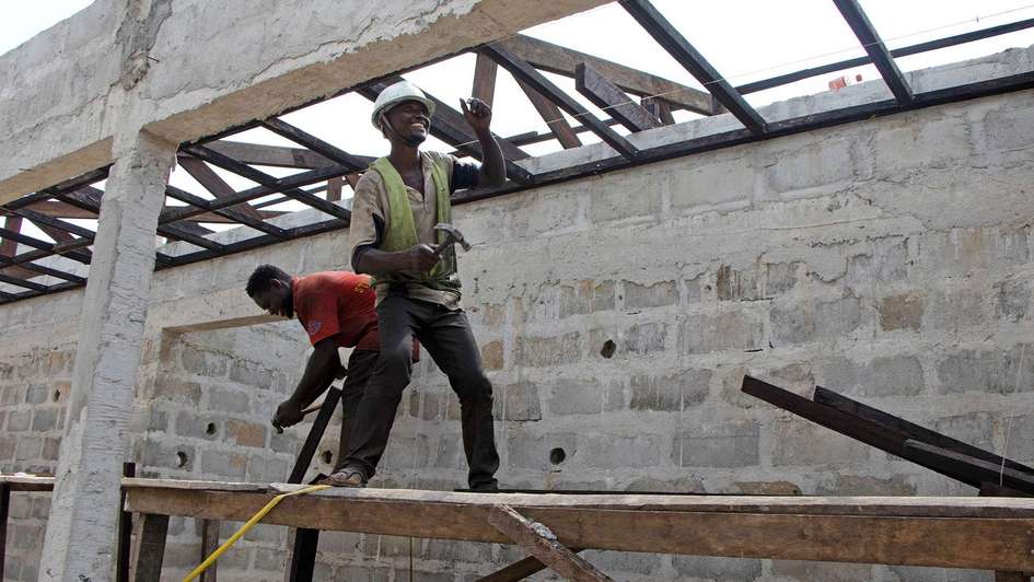 Two men on the scaffolding in the shell of a hospital in Liberia
