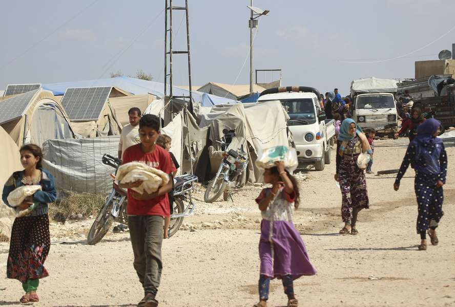 Refugees carry bags of bread in a refugee camp